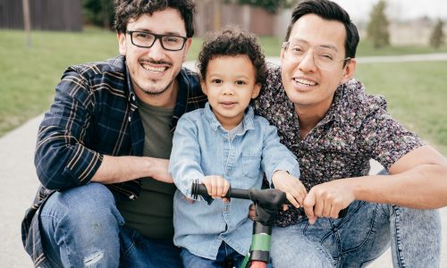 Two dads with toddler son having fun outdoor
